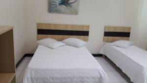 a bedroom with two beds with white sheets at Gv Park Hotel in Governador Valadares