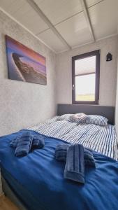 a bedroom with a bed with blue sheets and a window at Domki na wodzie Jastarnia - Houseboat in Jastarnia