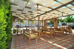 een patio met houten tafels en banken onder een paviljoen bij Likya Apart Hotel in Kemer