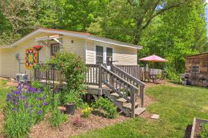 una casa pequeña con un porche de madera y flores en The Country Cottage in Union Mills with Porch! en Union Mills