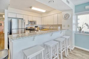 a kitchen with white cabinets and a counter with stools at East End Escape in Myrtle Beach