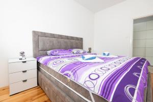 een slaapkamer met een bed met een paars dekbed bij Apartment Galiot in Kotor