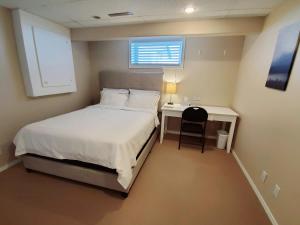 a bedroom with a bed and a desk and a window at Saskatoon Lashyn Cove Homestay in Saskatoon