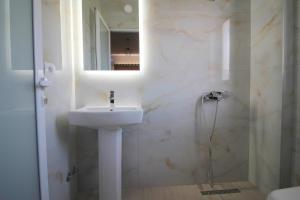 Baño blanco con lavabo y espejo en J&B Hotel en Ksamil
