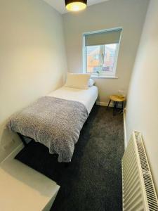 a small bedroom with a bed and a window at Newly refurbished 3 bedroom house in Heysham