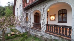een stenen huis met een veranda en een balkon bij Wrzos & Belvedere in Kudowa-Zdrój