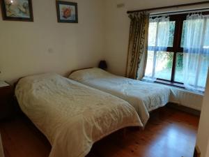 two beds in a bedroom with a window at Lovely Sea View 2-Bed Apt in Rineen Sleeps 4 in Skibbereen