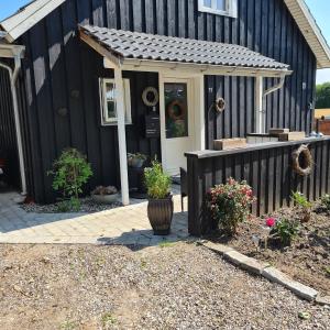 una casa negra con porche y valla en Marsvinslund bed and breakfast, en Viborg