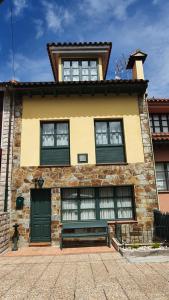 a building with a green door and windows at Casa de Aldea Las 7 gotas in Celorio