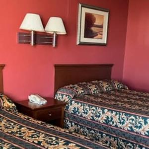 two beds in a hotel room with red walls at Budget Inn Wentzville in Wentzville