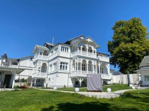 ein großes weißes Haus mit einem Tisch im Hof in der Unterkunft Villa Jenny Sassnitz Villa Jenny - Appartement 3 in Sassnitz