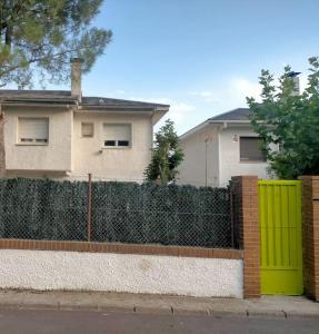 a fence with a green gate in front of a house at Chalet adosado con jardín in Cebreros