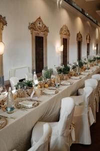 a long table in a room with white chairs at Hotel I Somaschi in Cherasco