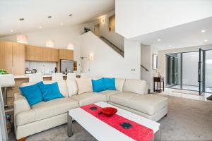 a living room with a white couch and blue pillows at Lakeview Retreat - Queenstown Holiday Home in Queenstown