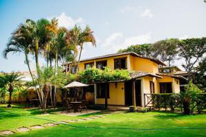 una casa gialla con tavolo e sedie in cortile di Pousada Village Porto Mirim pé na areia por Carpediem a Ceará-Mirim