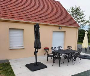 a patio with a table and chairs and an umbrella at Le Domaine de Louise in Seigy