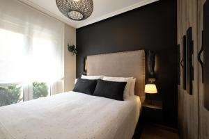 una camera da letto con un letto bianco e una parete nera di El Balconcillo - Boutique premium en pleno Gijón - Grupo Querbes a Gijón