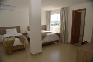 a hotel room with two beds and a window at Boa Esperança Apart Hotel in Boa Esperança