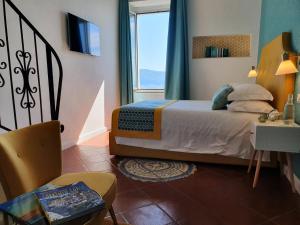 a bedroom with a bed and a window and a chair at Bella Vista House-Sorrento coast - free parking-solarium in Vico Equense