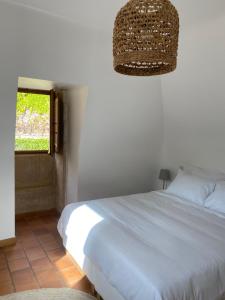 a bedroom with a white bed and a window at Les Courtines - Appartement de caractère à la Roque-Gageac - Les Charmilles in La Roque-Gageac