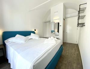 a bedroom with a large white bed with a blue headboard at L'Ulivo Comfort Rooms in Terrasini
