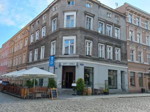 トルンにあるDomiApartのテーブルと椅子が前に置かれた大きな建物