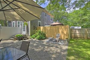 a backyard with a fence and a table and an umbrella at Cape Cod Getaway Fire Pit and Grill, 5 Mi to Beach! in Sandwich