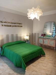 a bedroom with a green bed and a chandelier at Suite Liberty in Taranto