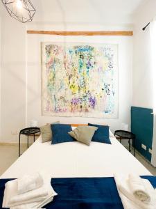 a bedroom with a large bed with a painting on the wall at DOMUS in Castellammare del Golfo