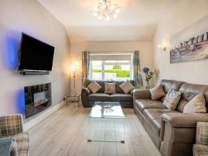 a living room with a couch and a tv and a fireplace at Captiva Cottage in Saundersfoot
