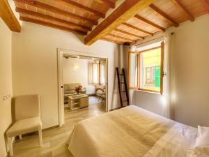 Un dormitorio con una cama y una silla y una ventana. en Il Buonumore, en Montepulciano
