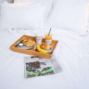 a tray of breakfast food on a bed with a magazine at YOTELAIR Singapore Changi Airport Landside in Singapore