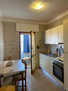 a kitchen with white cabinets and a table and a counter top at Incantevole appartamento Sole, in centro in Stintino