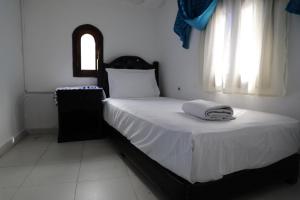 een slaapkamer met een bed met witte lakens en een raam bij Dar el Khzana in Chefchaouene