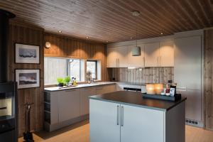 a kitchen with white cabinets and a wooden ceiling at Cozy modern holiday villa with electric car charging, sauna and fireplace in Øyer