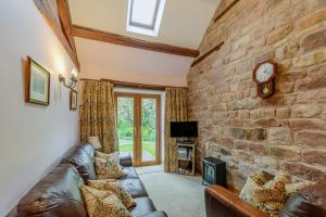 a living room with a couch and a stone wall at Wren Cottage in Leek