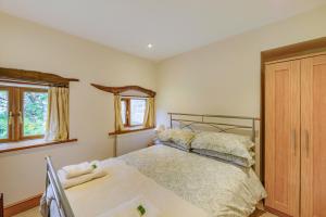 a bedroom with a bed and two windows at Wren Cottage in Leek