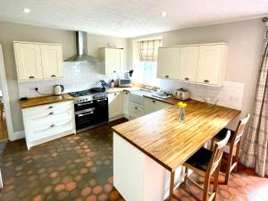 uma cozinha com armários brancos e um balcão de madeira em The Farm House em Llangollen