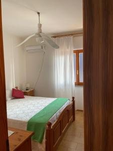 a bedroom with a bed with a green blanket at Incantevole appartamento Sole, in centro in Stintino