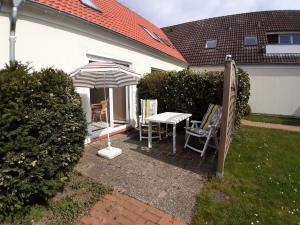 a patio with an umbrella and a table and chairs at Haus Strandgang, Whg 8 in Kellenhusen
