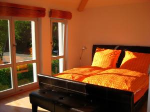 Schlafzimmer mit einem Bett mit orangefarbenen Wänden und Fenstern in der Unterkunft Ferienhaus in Heiligendamm mit Sauna & Kamin - [#23967] in Heiligendamm