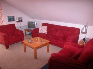 a living room with two red couches and a coffee table at Silva Mare, OG 1 in Kellenhusen
