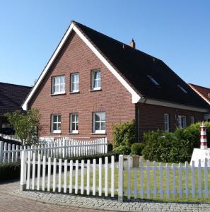 een wit hek voor een rood bakstenen huis bij Haus Jodokus, Whg Professor Paljass in Kellenhusen