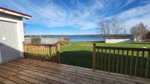 a wooden deck with a fence and a body of water at Trailsman Lodge in Baddeck