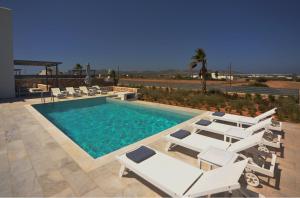 a swimming pool with white lounge chairs and a swimming pool at Blue diamonds villas Paros in Pounda