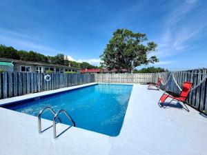 a swimming pool with two chairs and a fence at Trailsman Lodge in Baddeck