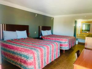Habitación de hotel con 2 camas y espejo en Budget inn and suites, en Crowley