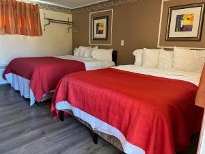 two beds in a hotel room with red and white sheets at Beachway Motel in Salisbury