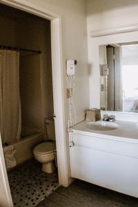 een badkamer met een bad, een toilet en een wastafel bij Devonshire Inn Motel in Rosamond