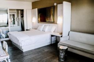 een slaapkamer met een wit bed en een bank bij Devonshire Inn Motel in Rosamond